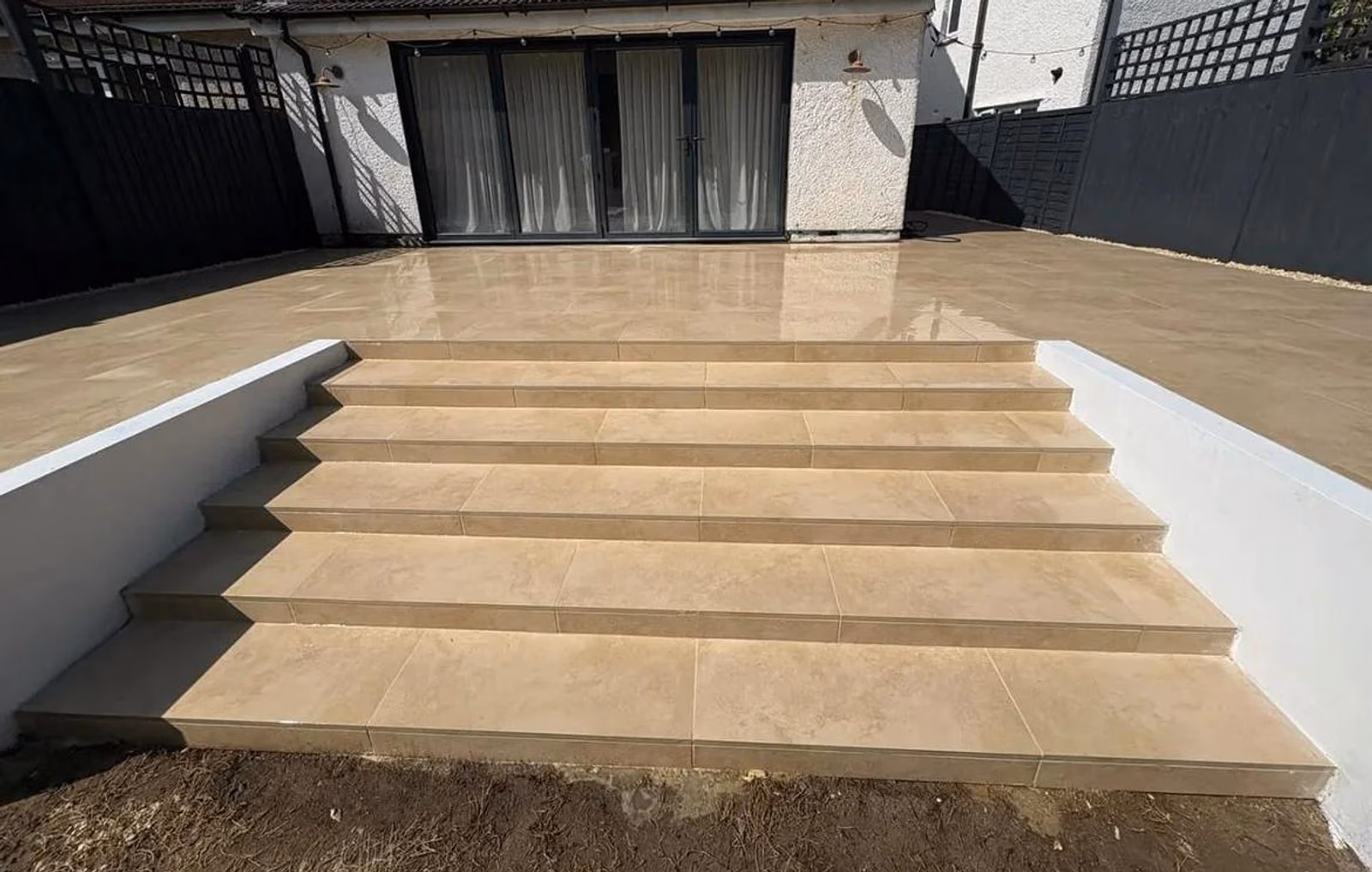 A raised porcelain patio with broad steps installed by Teddington Landscapes